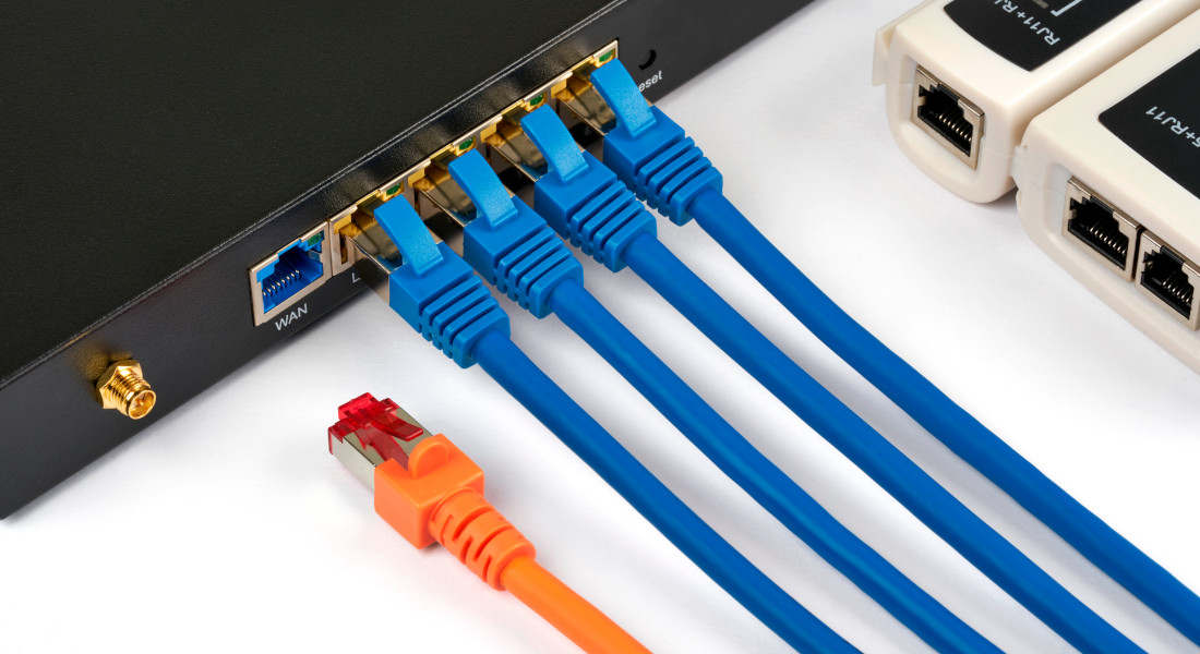 Netværksswitch med tilsluttede blå netværkskabler og et orange netværkskabel.