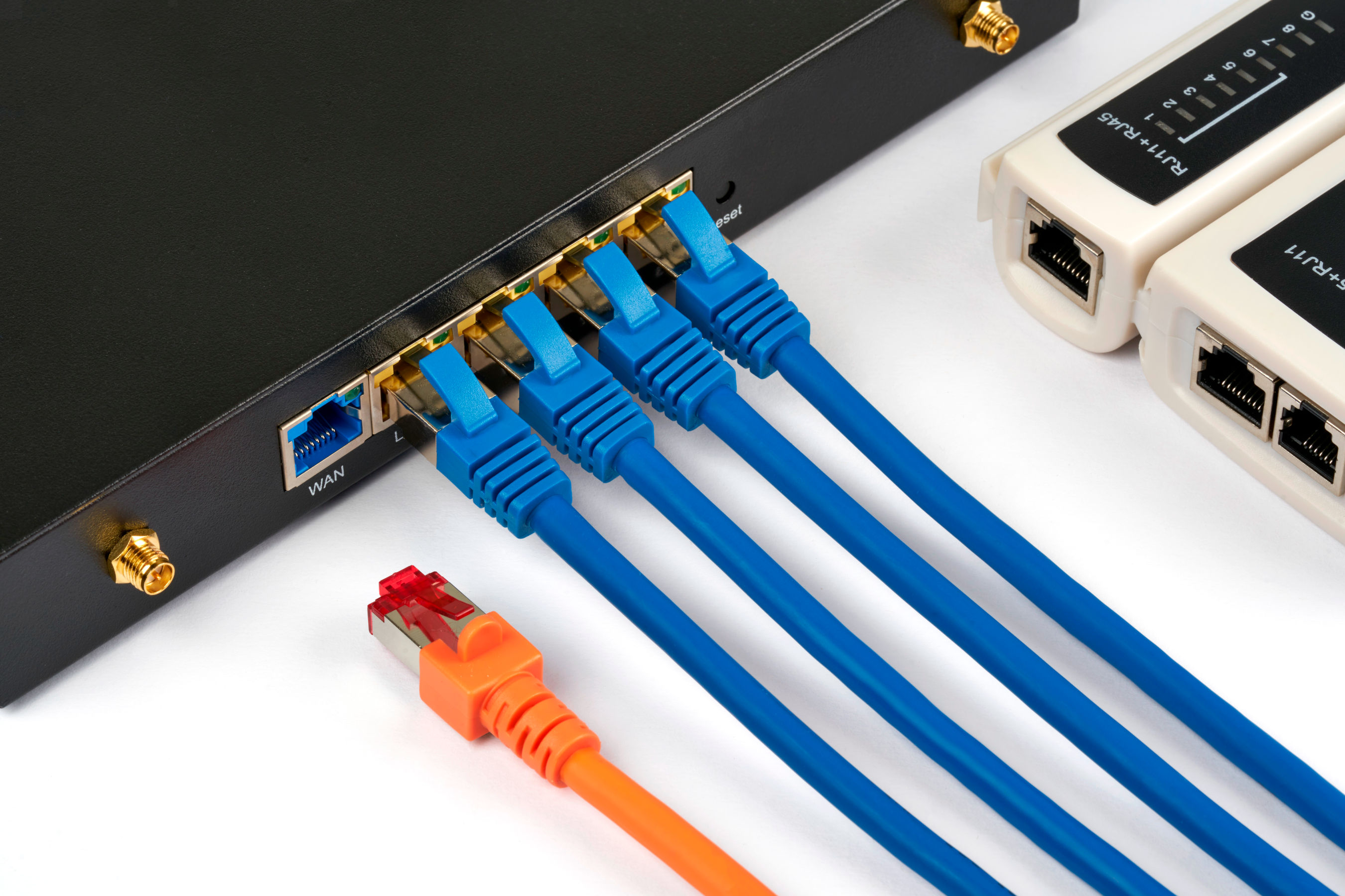 Netværksswitch med tilsluttede blå netværkskabler og et orange netværkskabel.